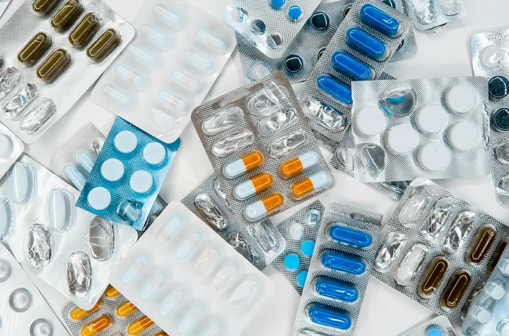 A white table that is covered in various medications and pills still in their packaging.